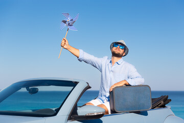 Successful young businessman on a beach. Man sitting in the cabriolet classic car.