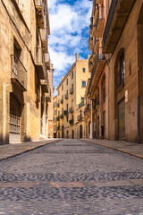 Obraz premium Low angle view of small alley in pedestrian area in old town of Tarragona city, on a sunny day in summer, Tarragona, Catalonia, Spain