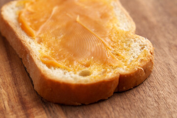 Slice of whole grain bread with smooth layer of vegan sweetened condensed coconut paste on wooden table. Healthy vegetarian snack