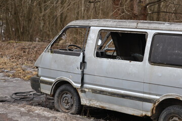 A van parked in the dirt, possibly abandoned or broken down.