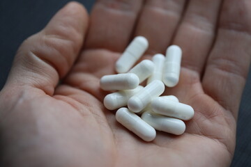 A person holding a handful of pills in their hand.