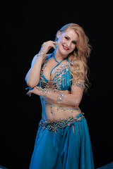 Woman in a blue costume oriental dancer posing and dancing on a black background
