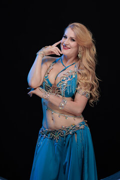 Young woman belly dancer in a red oriental costume on a black background