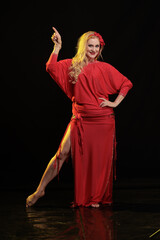 Fototapeta premium Dancer girl with long hair in red oriental costume posing and dancing on black background