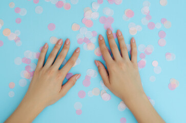 Women's nude manicure on a blue background. Beauty and health. Beauty procedure. Women's hands.