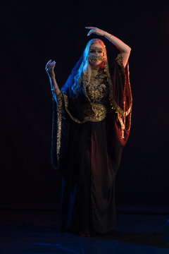 woman with long hair in oriental dancer costume posing and dancing on a black background