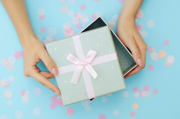 Well-groomed female hands hold a gift on a blue background. Festive background. Surprise.