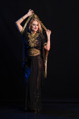 girl with long hair in oriental dancer costume posing and dancing on a black backgroun