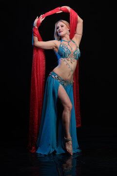 Young woman belly dancer in a blue oriental costume on a black background
