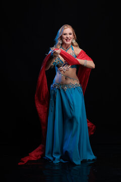 Young woman belly dancer in a blue oriental costume on a black background