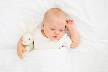 cute little newborn baby sleeping under a blanket hugging a plush bunny, sweet healthy baby sleep...
