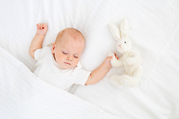 cute little newborn baby sleeping under a blanket hugging a plush bunny, sweet healthy baby sleep in a white crib, a place for text