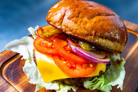 Juicy burger with fresh toppings on wooden board