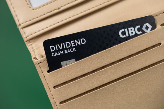 Poznan, Poland - February 26, 2025: CIBC Dividend cash back credit card in a beige leather wallet on a green background, financial rewards, modern banking, fintech, digital payments