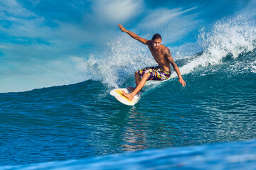 Male surfer on a blue wave at sunny day