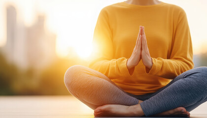 Meditation practice at sunset, showcasing person in yellow sweater and gray leggings, hands in prayer position, promoting mindfulness and tranquility