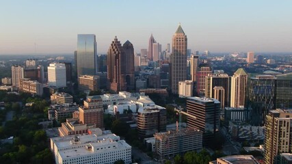 Cinematic aerial footage of the Midtown Atlanta skyline at sunset, with golden hour lighting, glowing skyscrapers, and a vibrant mix of natural and urban beauty.