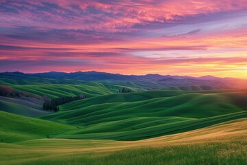 Fototapeta premium Vibrant landscape showcasing rolling green hills and colorful sky at sunset over majestic mountains
