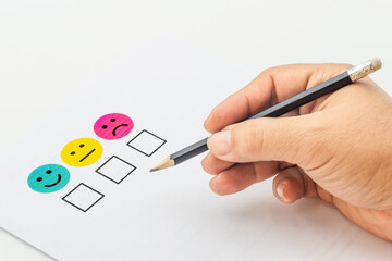 Customer satisfaction survey response with smiley faces and pencil
