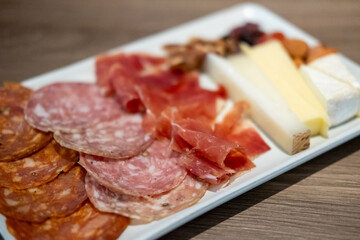 Cold cuts platter, variety of sliced meat and cheese with olives and nuts