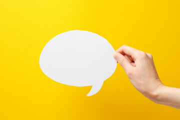 Woman holding blank speech bubble on yellow background, closeup. Space for text