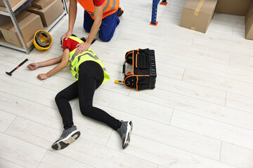Accident at work. Man helping his unconscious colleague in warehouse. Space for text