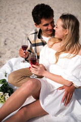 young couple in love on a picnic on the ocean shore drinking wine