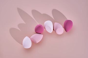 A set of makeup sponges on a pink background.