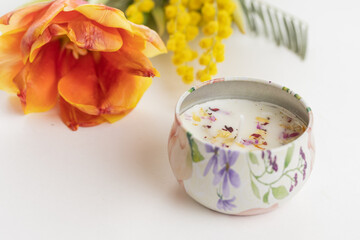 A floral candle, orange yellow flowers. Spring home decor, relaxation and aromatherapy.