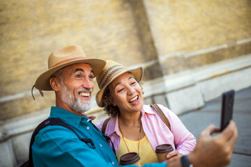 Obraz premium Elderly married couple taking a selfie with their coffee. Tourists exploring the new city.