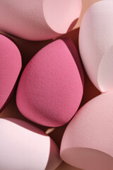 A set of makeup sponges on a pink background.