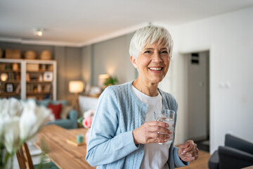 Elderly woman drinking water and looking at camera