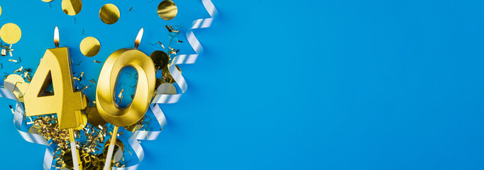 Celebrating 40 years. Golden burning candle in form of number forty on celebration festive blue background lying in sparkles. Holiday banner