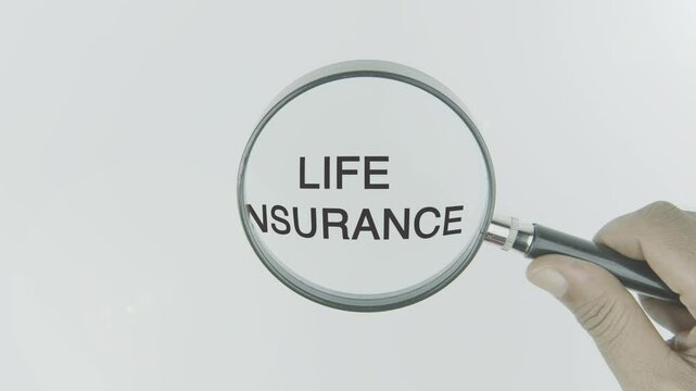Life insurance text or word highlighted by a magnifying glass in a hand on a white background, symbolizing financial protection, future planning, and support for loved ones in case of death