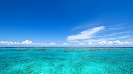 Obraz premium Aerial View of Turquoise Ocean Water Under a Bright Blue Sky with White Clouds along the Horizon
