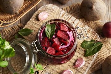 Glass jar filled with slice beetroot, onions, garlic and spices - preparation of fermented beet kvass
