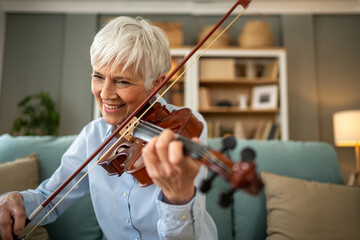 Woman playing the violin while relaxing on her sofa