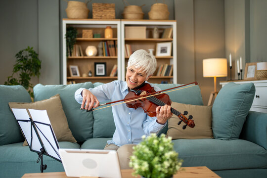 Senior woman playing violin during online class at home