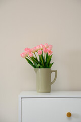 A beautiful arrangement of pink tulips displayed in a ceramic vase placed on a white table.