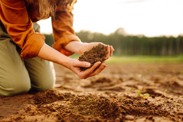 Close-up of farmer's hands holding fertile soil. Young female agronomist checking soil quality...