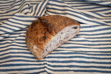 Rustic whole-grain sourdough bread with a crispy crust and airy crumb, resting on a striped linen cloth.