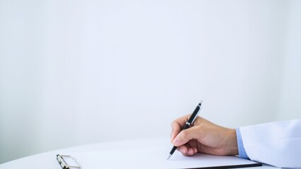 A doctor writing on a piece of paper with a black pen on a white surface. The minimalist scene highlights the writing action and the neat, professional workspace