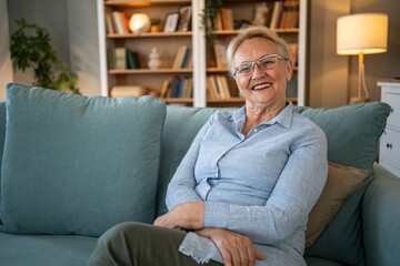 Obraz premium Happy senior woman smiling sitting on sofa at home