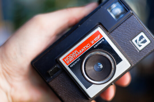 A close-up lifestyle shot of a vintage Kodak Instamatic X-15F camera held in hand, showcasing its classic design and retro aesthetic
