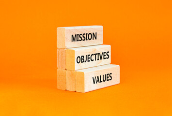 Naklejka premium Mission objectives values symbol. Concept words Mission Objectives Values on beautiful blocks. Beautiful orange table orange background. Business mission objectives values concept. Copy space.
