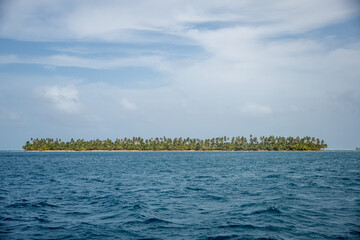 Island covered in palm trees, surrounded by clear blue water, in the San Blas Islands, off the Caribbean coast of Panama