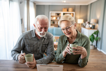 Older couple spending time together with coffee and tablet