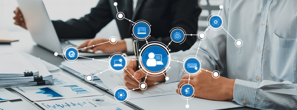 Two business professionals work together in an office environment, showcasing digital connectivity and data analysis tools for effective collaboration and project planning. Amity