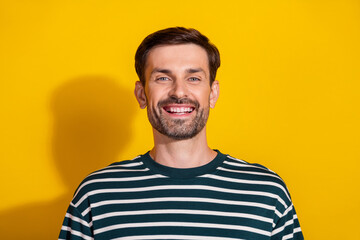 Obraz premium Portrait of a cheerful young man in a casual striped shirt against a vibrant yellow background