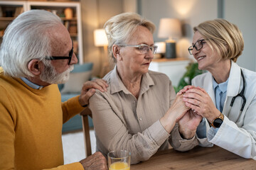 Senior couple receiving comforting support from doctor at home